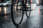 Bicycle wheel with twin skinny tires slicing through a wet city street